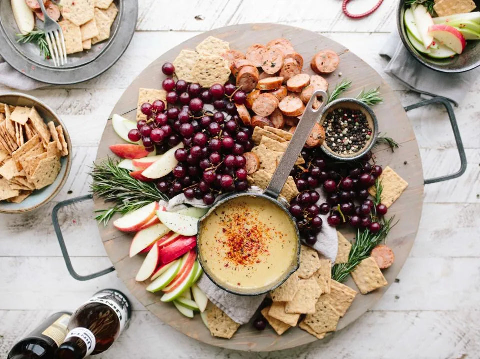 Grand plateau à partager : houmous, crackers, fruits, fromage et charcuterie